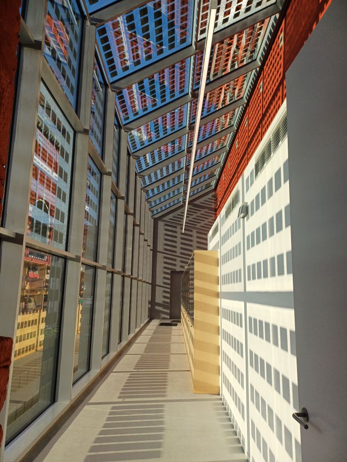 Bright indoor corridor showcasing striking geometric patterns from glass panel reflections.